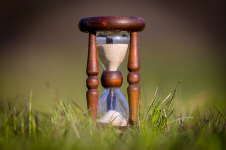  old hourglass among green grass on meadow