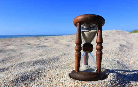 vintage hourglass on the sand under the blue skyの写真素材