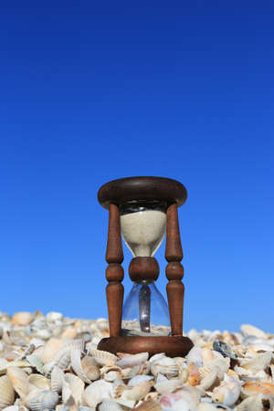 old hourglass on seashells on clear blue sky backgroundの写真素材