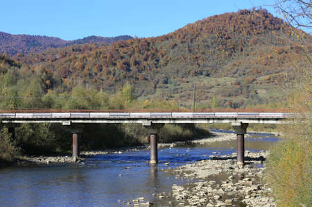 Autumn landscape with bridge over mountain river