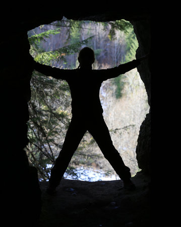 profile of the figure of a young man in the opening of a cave in the forestの写真素材