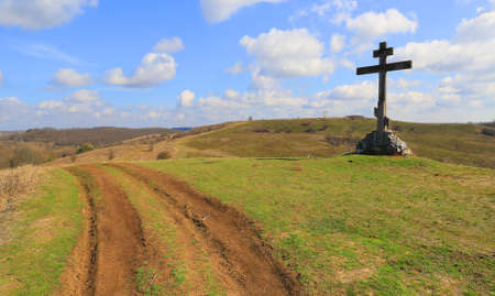 rural road near cross on green hillの写真素材