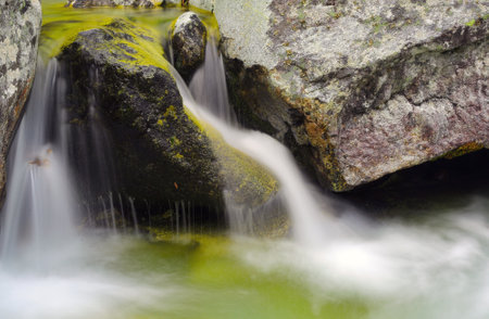 small waterfall on brook in mountainsの写真素材