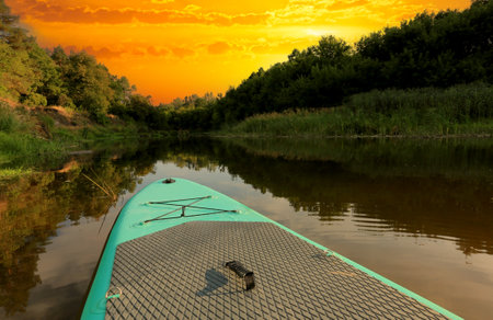 evening landscape with SUP board on the river in forest