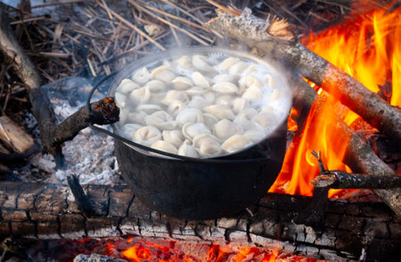 dumplings are boiled in a pot over a fire in forest campの写真素材