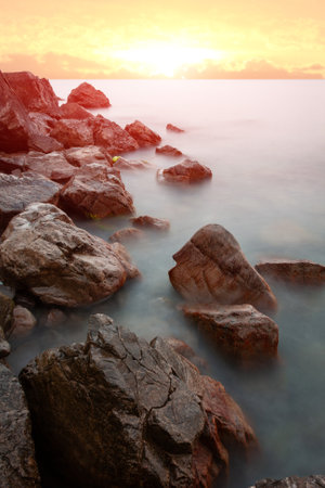 Landscape with wet stones in sea water on sunset backgroundの写真素材