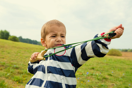 A boy learns to shoot a slingshotの写真素材