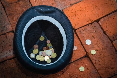 Black hat with euro coins on a brick backgroundの写真素材