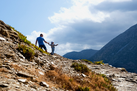 Man with a child walks through the mountains on a sunny summer dayの写真素材