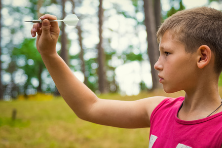 Portrait child outdoors. Teen takes aimの写真素材