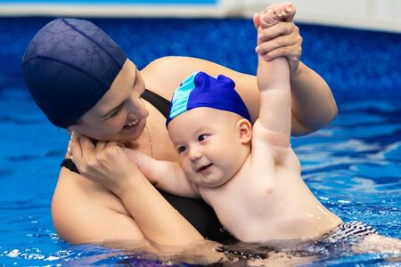 Sports family. A woman with a child in the pool. The baby learns to swim
