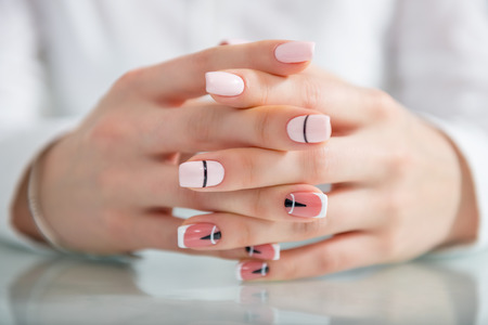 Beautiful female hands with a fashionable manicure. Geometric design of nails. Photo closeupの写真素材