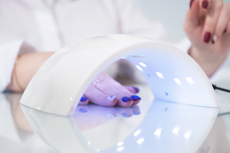 Female hand close up. Manicure. Ultraviolet lamp for drying nail polish. Photo indoorsの写真素材