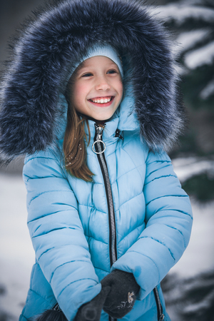 Portrait of a beautiful little cheerful girl. A child in the winter outdoorsの写真素材