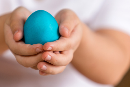 Easter. Painted egg in the hands of a child. Photo closeupの写真素材
