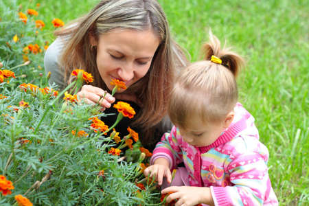 Happy Mom and daughter sniffing flowers in the gardenの写真素材