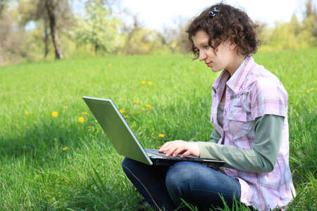 Girl with a laptop on the spring meadowの写真素材