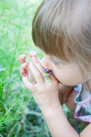 A little girl is smelling the blooming flowers. の写真素材