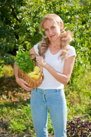 A Young woman holding vegetables in the gardenの写真素材