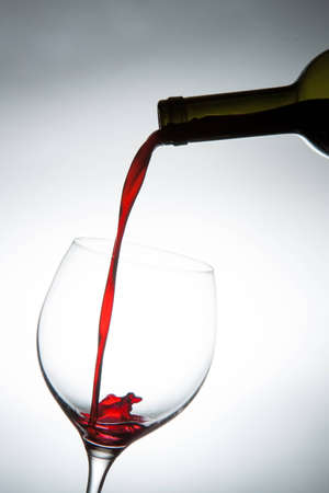 Pouring red wine into a glass.の写真素材