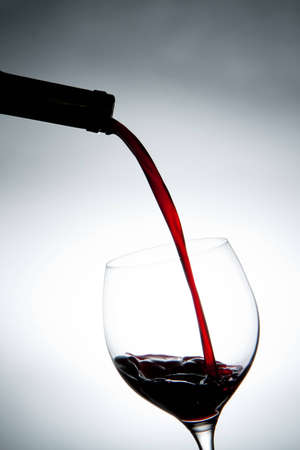 Pouring red wine into a glass.の写真素材