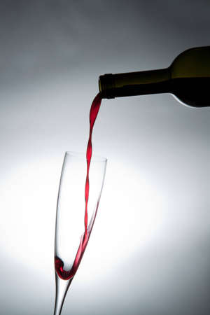 Pouring red wine into a glass.の写真素材