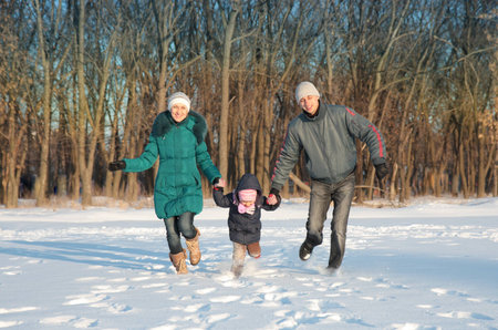 Family running in park holding hands smilingの写真素材