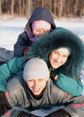 happy family lying on the snow in the winterの写真素材