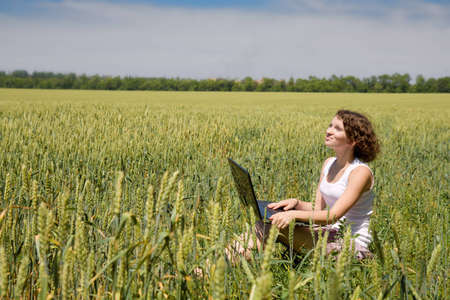 Woman with laptop sitting in a fieldの写真素材