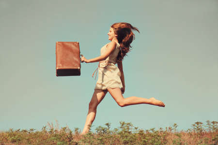 Young girl jumping with a suitcase.の写真素材