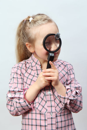 Funny girl explores with a magnifying glass の写真素材