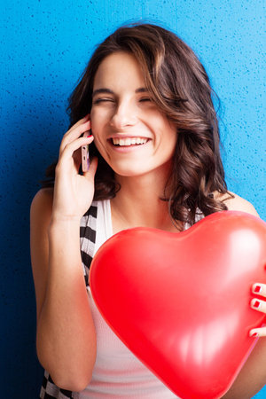 Love and valentines day woman holding heart smiling cute and adorable on blue background. Beautiful caucasian woman in love.の写真素材