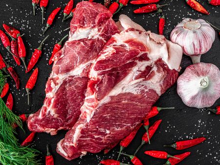 two pieces of fresh marbled beef on a dark background, with spices for cooking steak, Black background. Top view.の写真素材