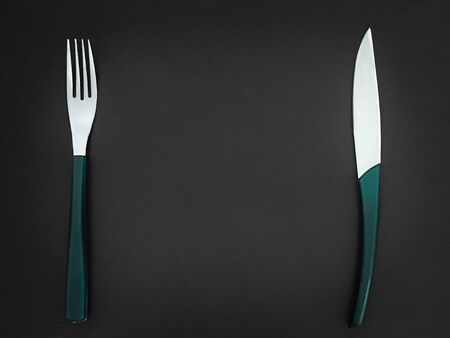 Cutlery set on a dark background, stylish green cutlery on dark stone with copy space. Concept...