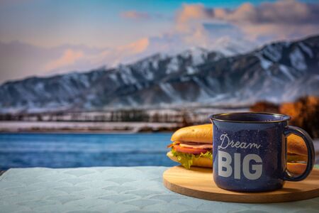 Morning cup of coffee and sandwich with mountain background at sunrise,の写真素材