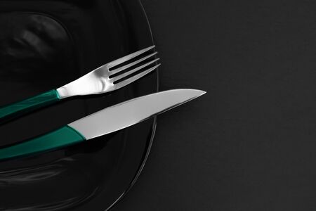 Empty black slate plate, cutlery on dark stone table and napkin. Food background for menu, recipe. Table setting. Flatlay, top view. Concept modern shooting menuの写真素材