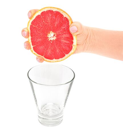 The female hand squeezes out juice from a ripe grapefruit. Isolation on white.の写真素材