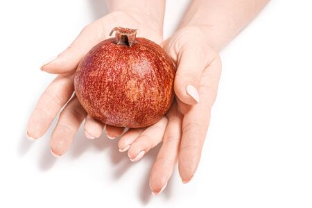 bright pomegranate in the hands of a girl on a white background. Woman holds ripe pomegranate fruit. Concept: fruit diet, isolatedの写真素材