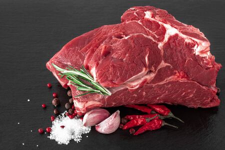 a piece of raw beef meat on a dark cutting boardの写真素材