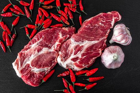 Fresh steaks from Raw pork meat on dark stone background, Top view, food conceptの写真素材