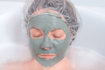 Portrait of a woman in facial mud mask lying in the bath. Face Skin careの写真素材