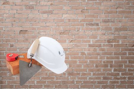 brick, white hard hat, Trowel tape measure. On brick wall background. construction concept. copyspaceの写真素材