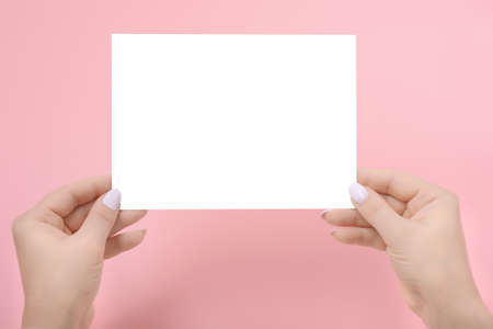 Woman's Hands holding Paper flyer A5 mockup on pink. Mockup of a empty sheet of paperの写真素材