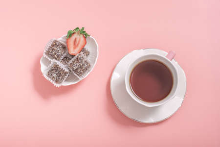 Tea in a white cup, saucer and bowl of sweets on a pink background. low calorie sweets dessert...