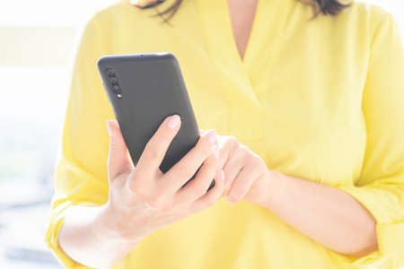 Close up of women's hands holding cellphone smartphone. Woman use of cellphone. Indoor. copy space for your advertising text message or promotional contentの写真素材