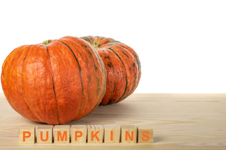 two pumpkins on a wooden table. the word PUMPKINS is laid out in wooden cubes. agriculture pamkin conceptの写真素材