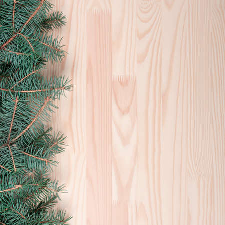 Christmas wooden background with snow fir tree. Light wood background with fir branches. Space for a greeting message. square Christmas card. Top view. Spruce Branches With boardの写真素材