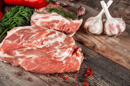 Raw pork on a chopping board on a dark wooden surface and spice for cooking. Food background. Raw meat on a wooden chopping boardの写真素材