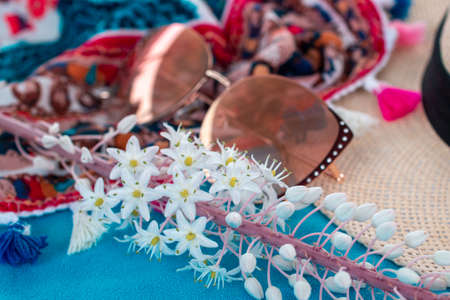 composition of sun hat, sunglasses, flower and pareo on blue beach towel. summer vacation by the sea...
