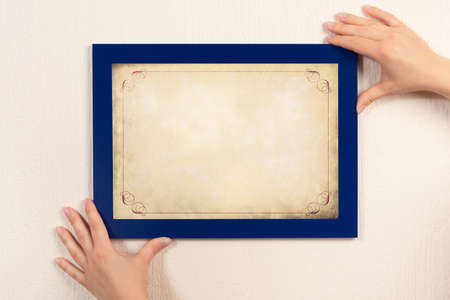 mockup diploma. woman hanging photo frame mockup on wall. OLD grunge certificate with vintage...